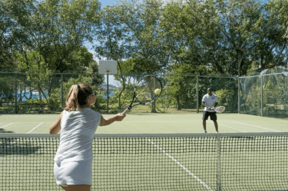 Two guests play tennis in winter in the Caribbean during their stay at one of our luxury Caribbean vllas.