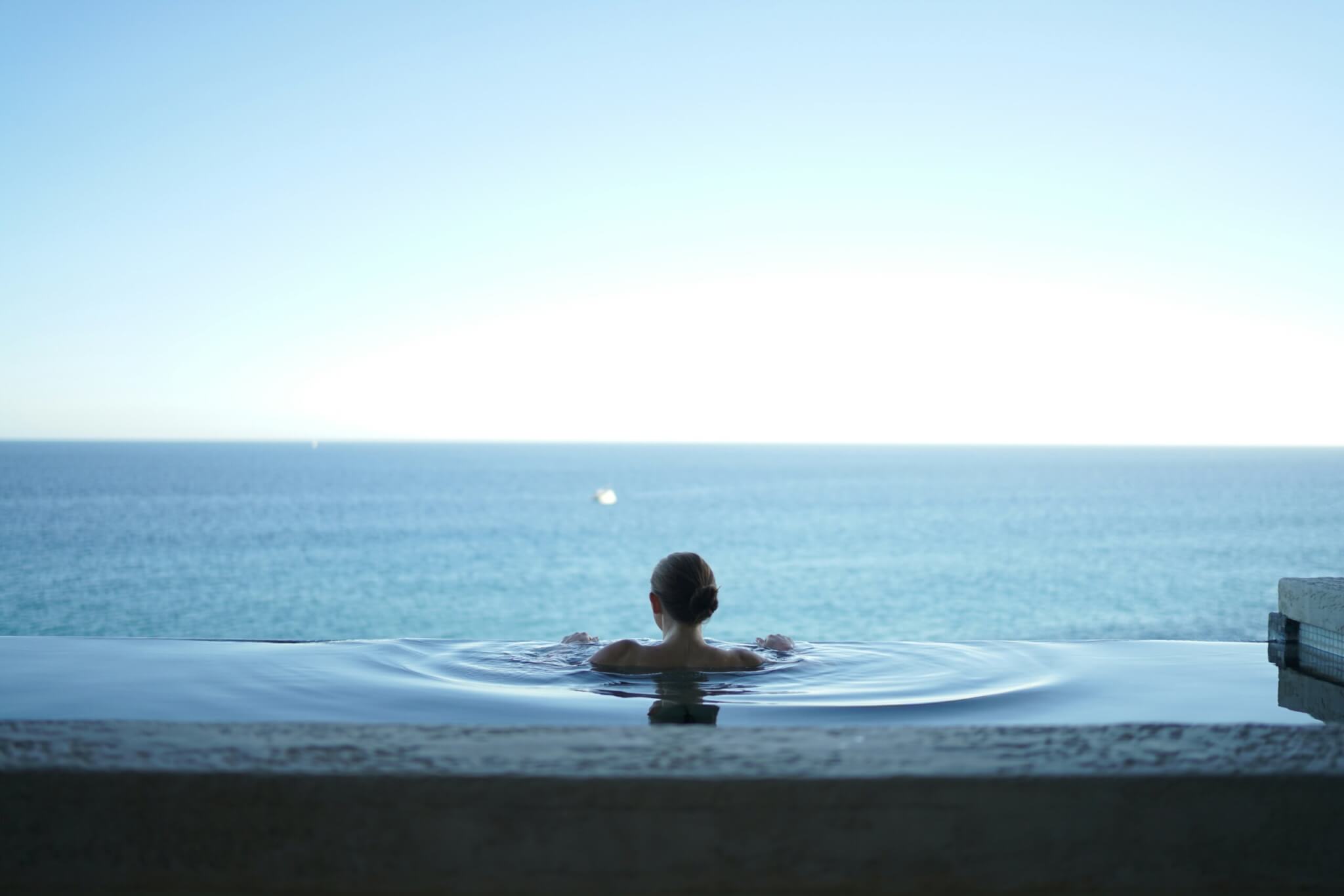 Woman in a pool overlooking the sea in Santorini