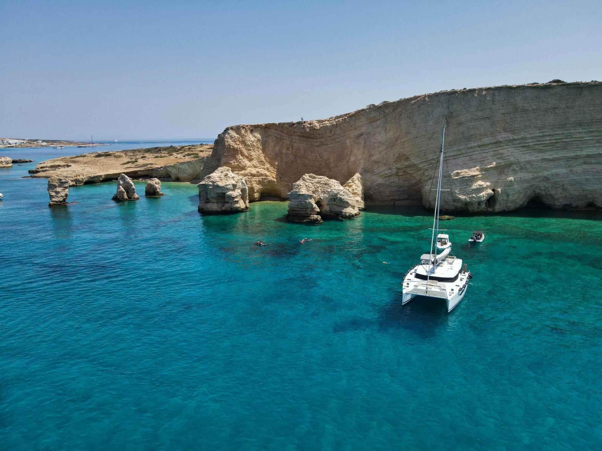 a catamaran and a rugged coastline with caves