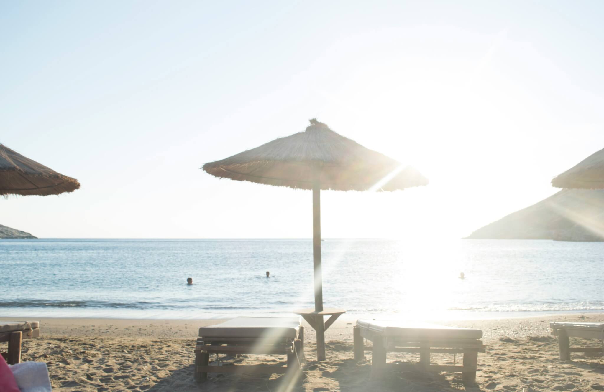 two sun chairs and an umbrella at the beach