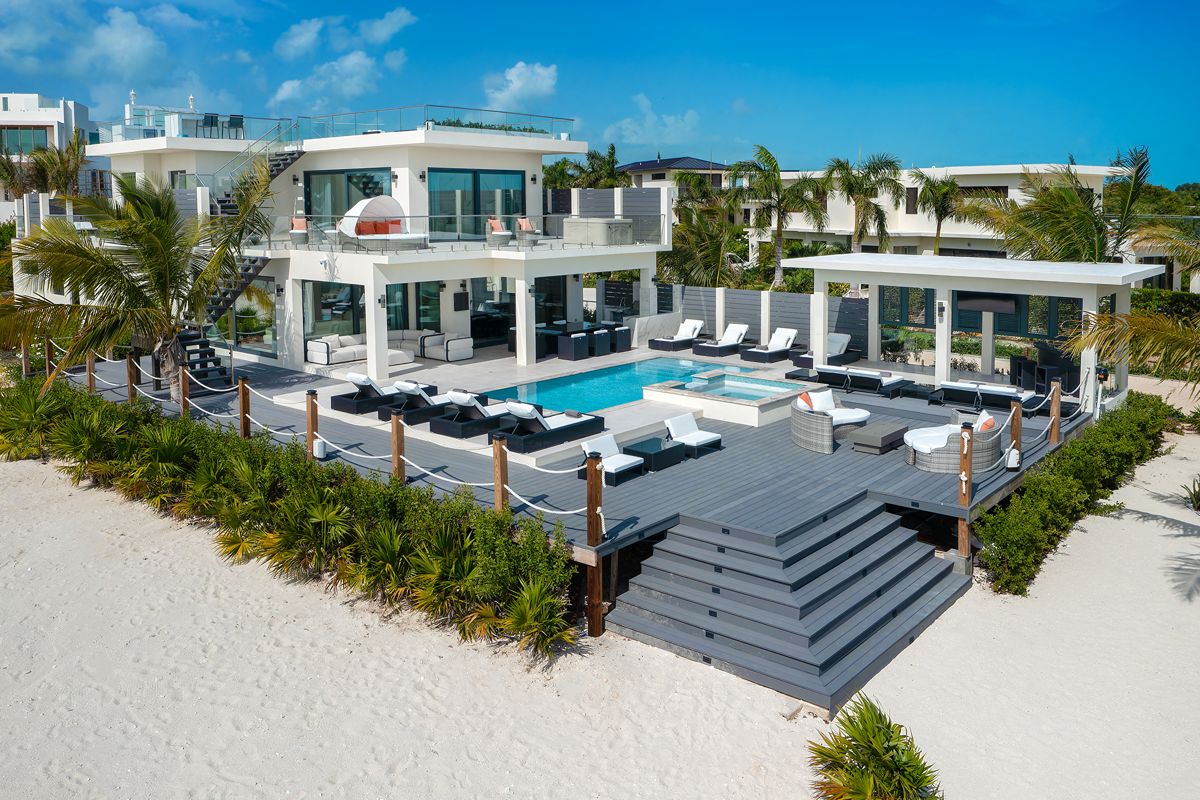 A two-storey Taylor Bay Oceanfront Villa featuring a deck, swimming pool, hot tub, and outdoor seating area.
